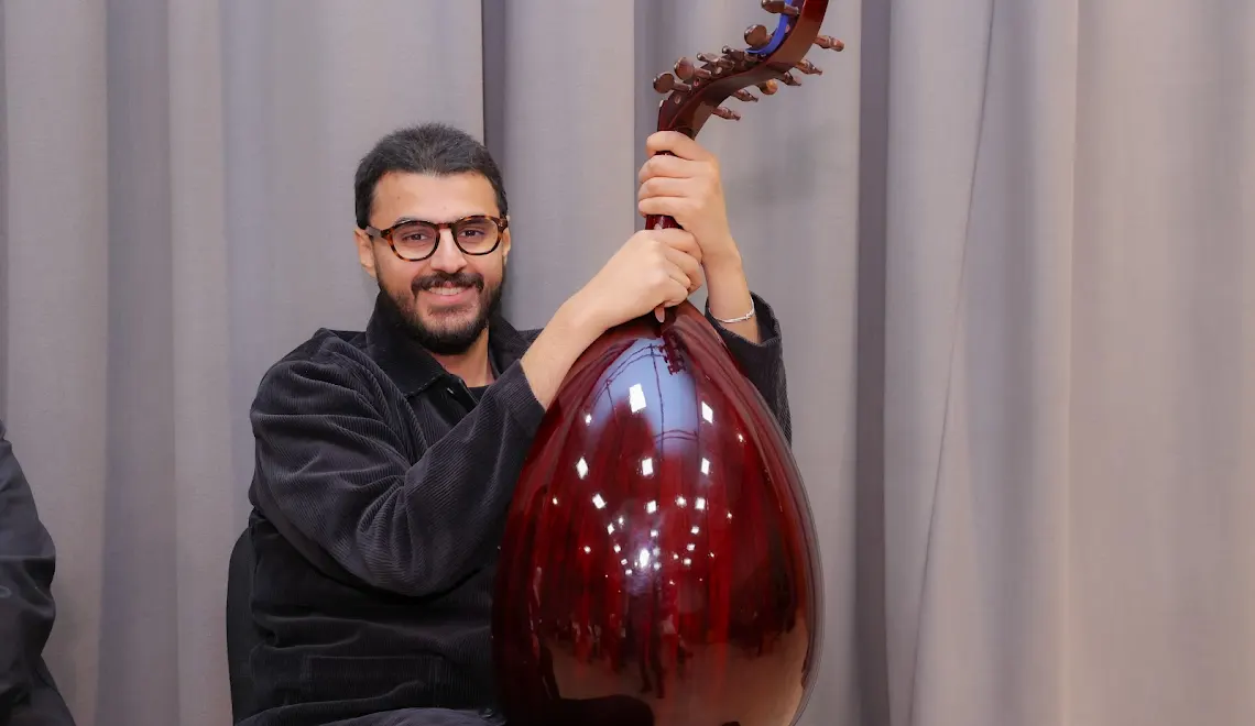 عازف عود يحمل آلته بابتسامة في استوديو المركز